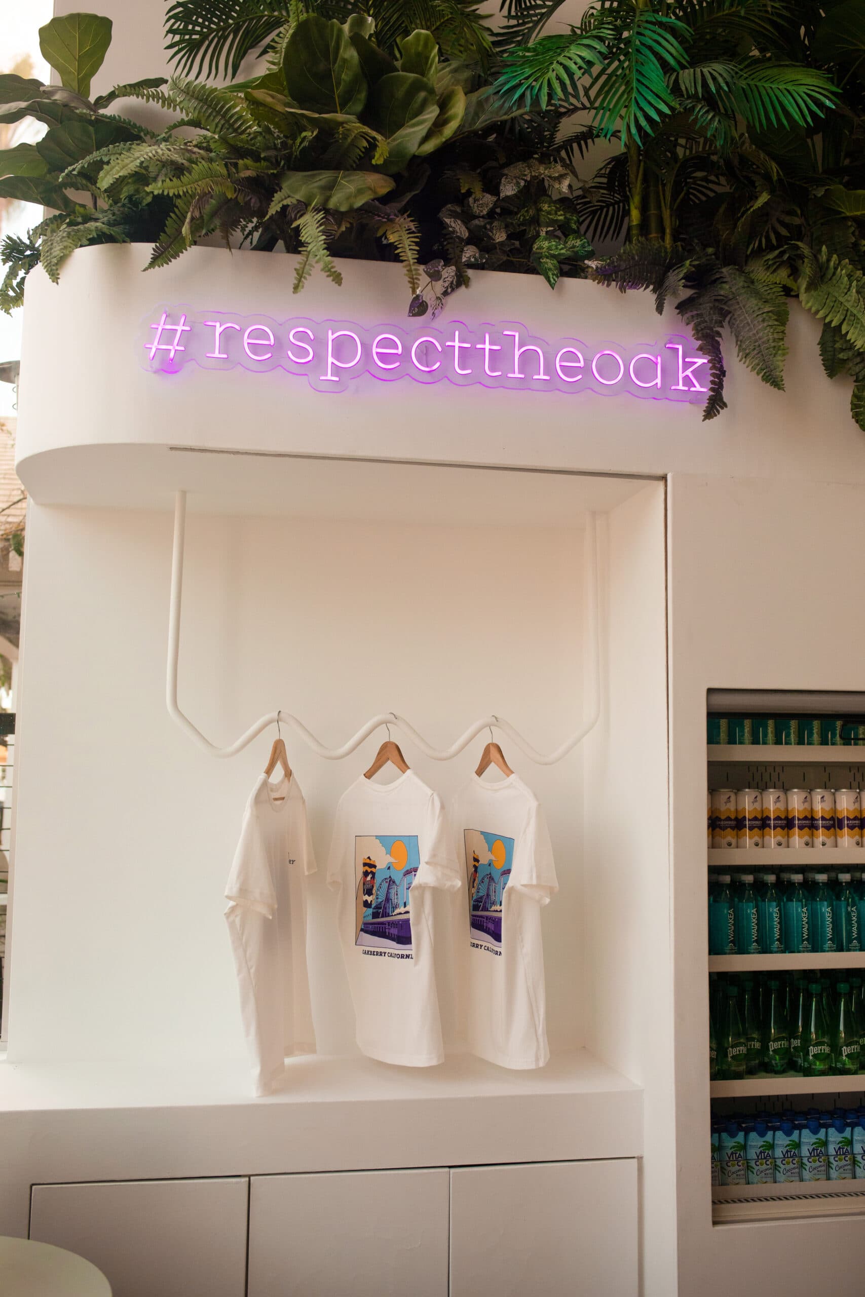 A OAKBERRY store with white t-shirts on swingers and purple neon sign